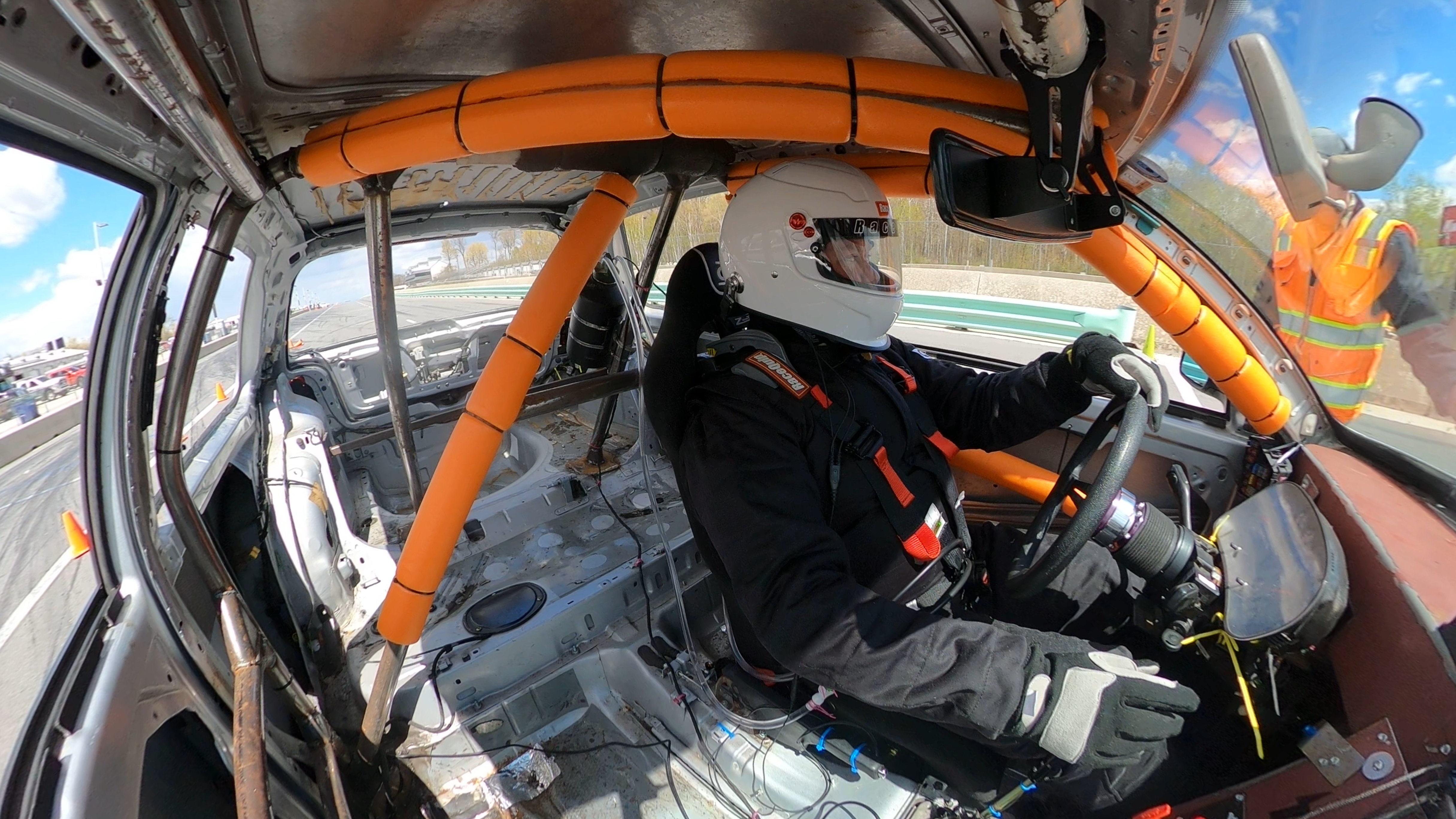 Interior view of the GTI cockpit with orange roll cage and driver strapped in